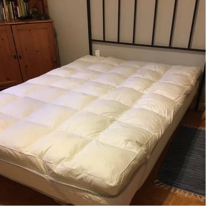 a reviewer photo of the white mattress topper on bed