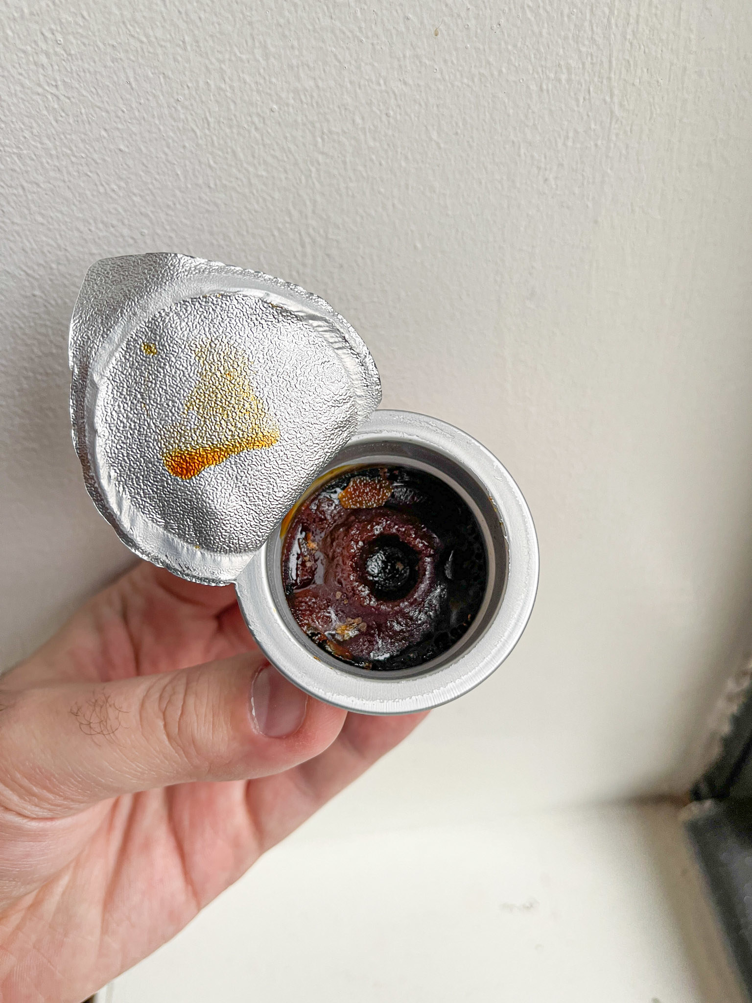 frozen coffee concentrate in an aluminum pod with aluminum lid peeled back three quarters of the way