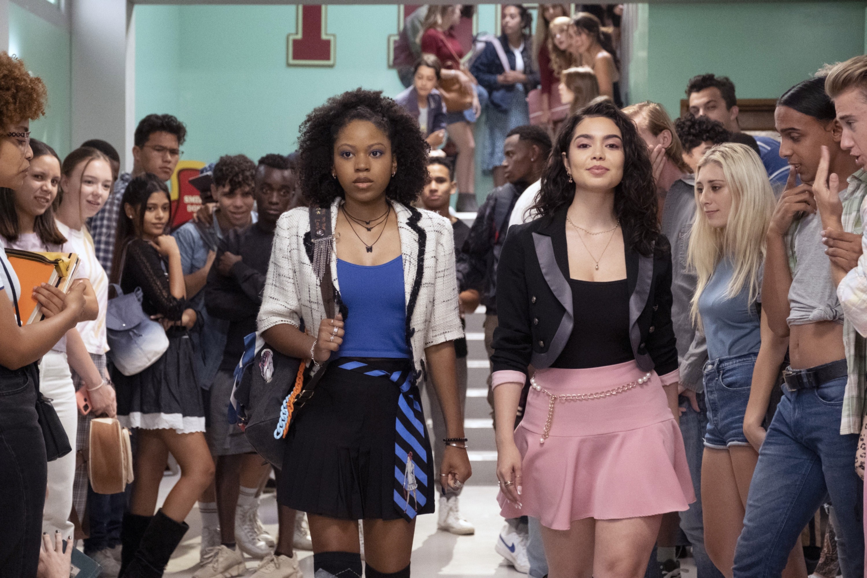 Riele Downs and Auli’i Cravalho walking down the school hallway.