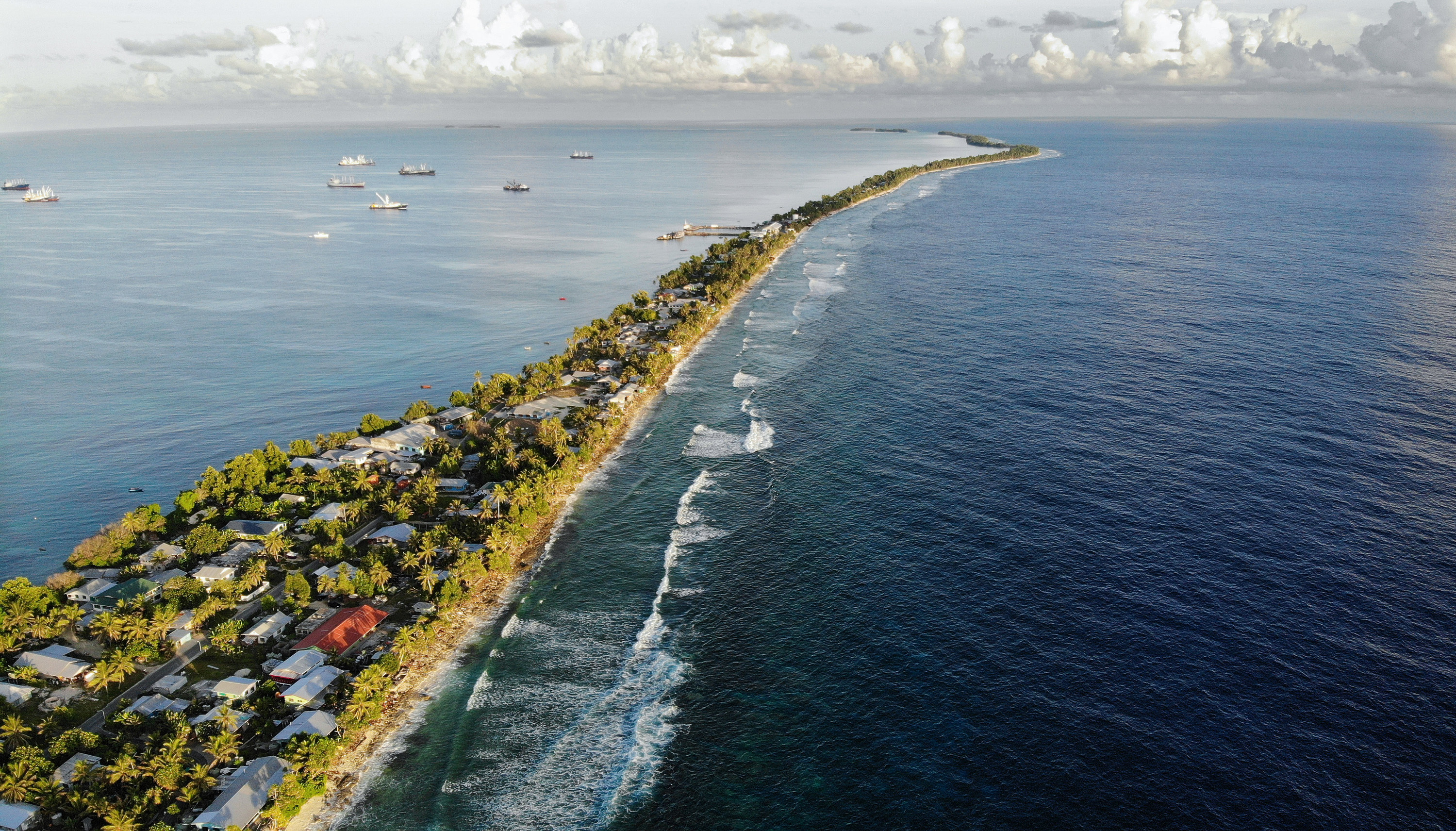 An aerial view of a strip of land between the Pacific Ocean and lagoon in Funafuti, Tuvalu