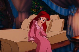 Ariel from The Little Mermaid sitting on the edge of a bed