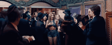 Movei gif: Margot Robbie in a shimmery blue two-piece surrounded by reporters
