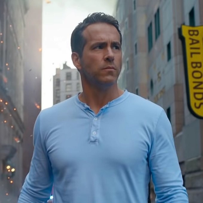 Ryan Reynolds shaved wearing a blue shirt in Free Guy.