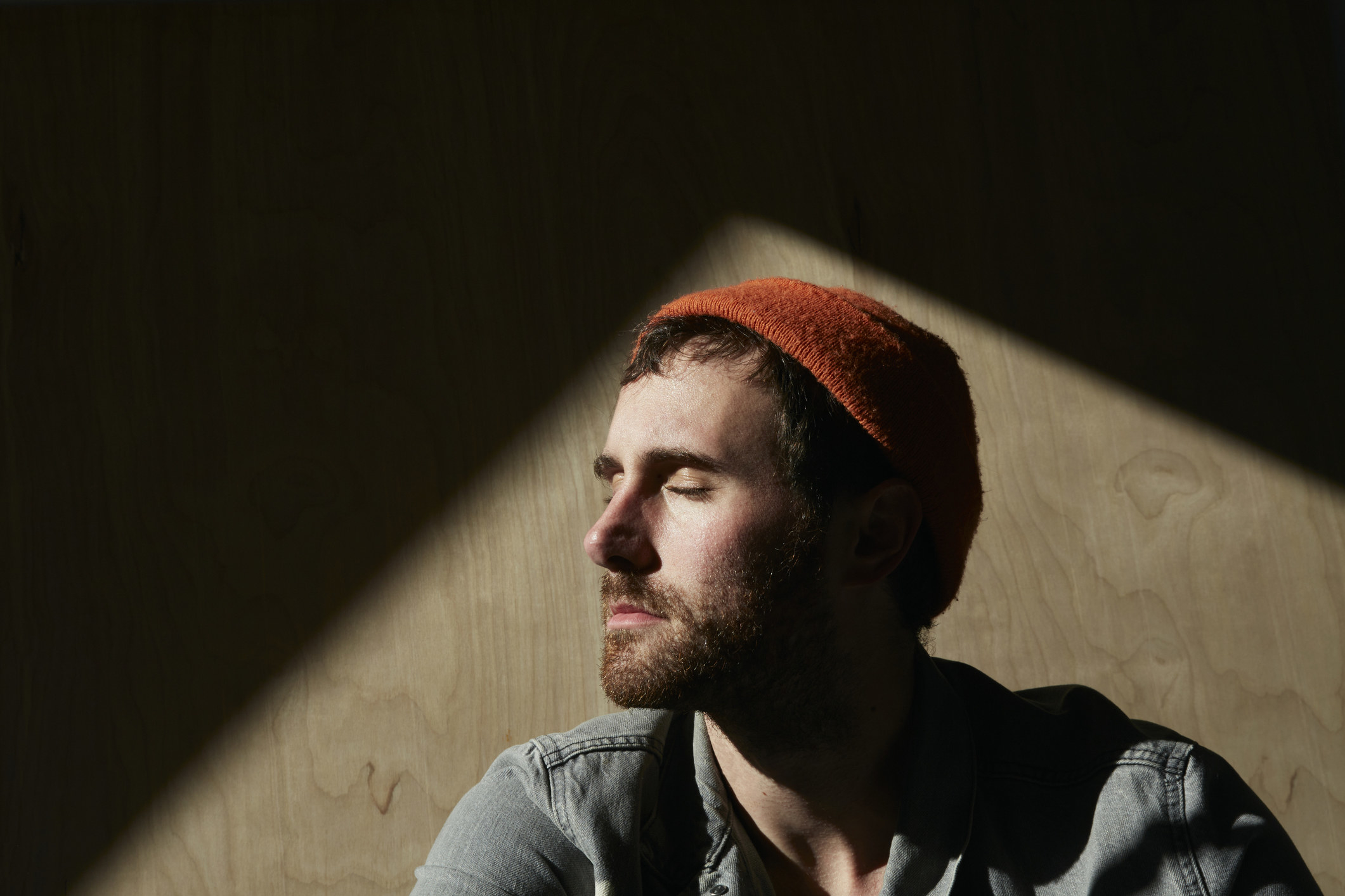 A young man with his eyes closed in a dimly lit room