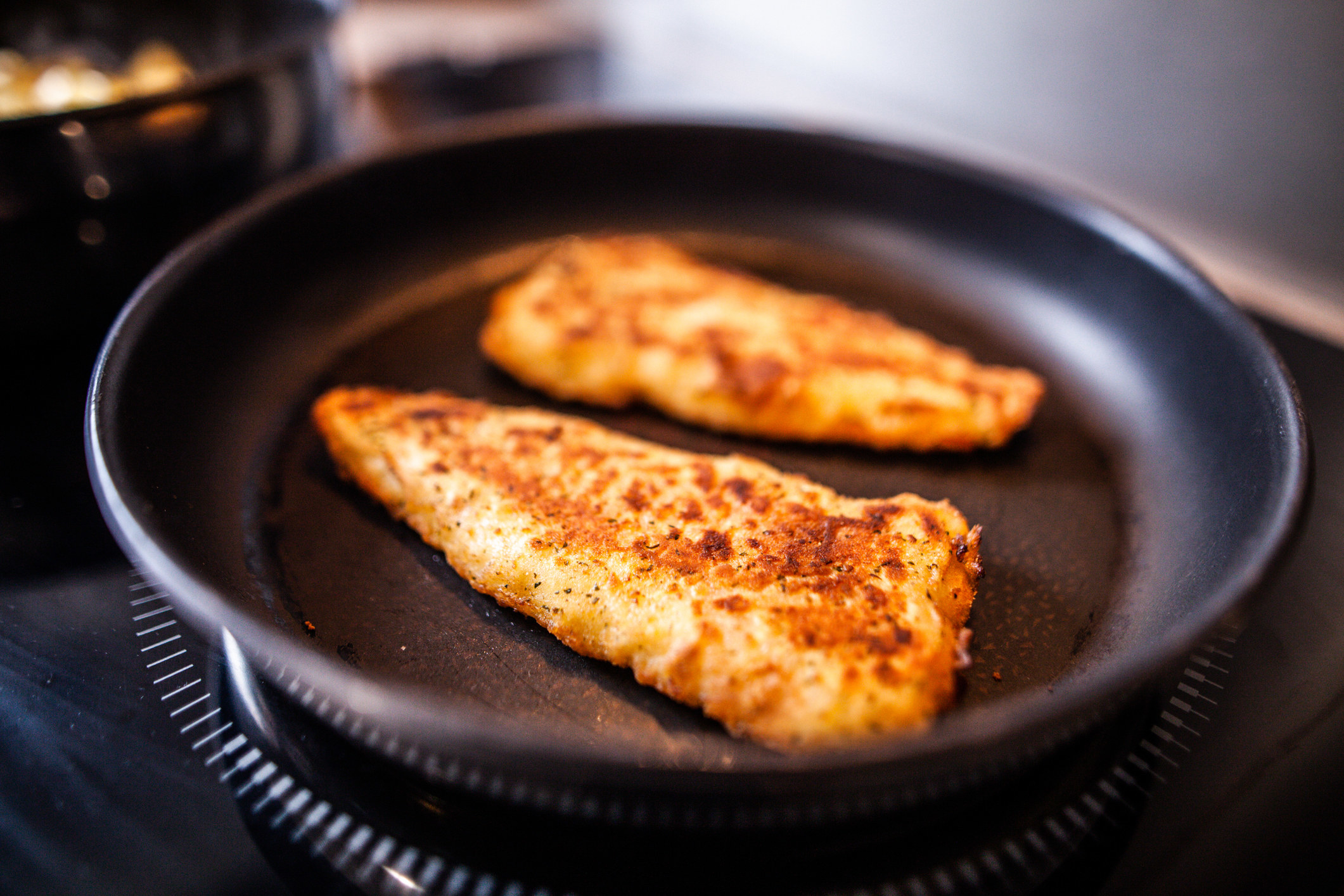 Two breaded chicken cutlets in a skillet