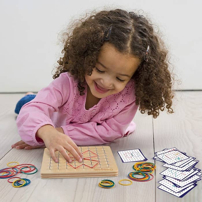 a kid playing with the geoboard
