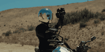 A man with a mirrored motorcycle helmet records