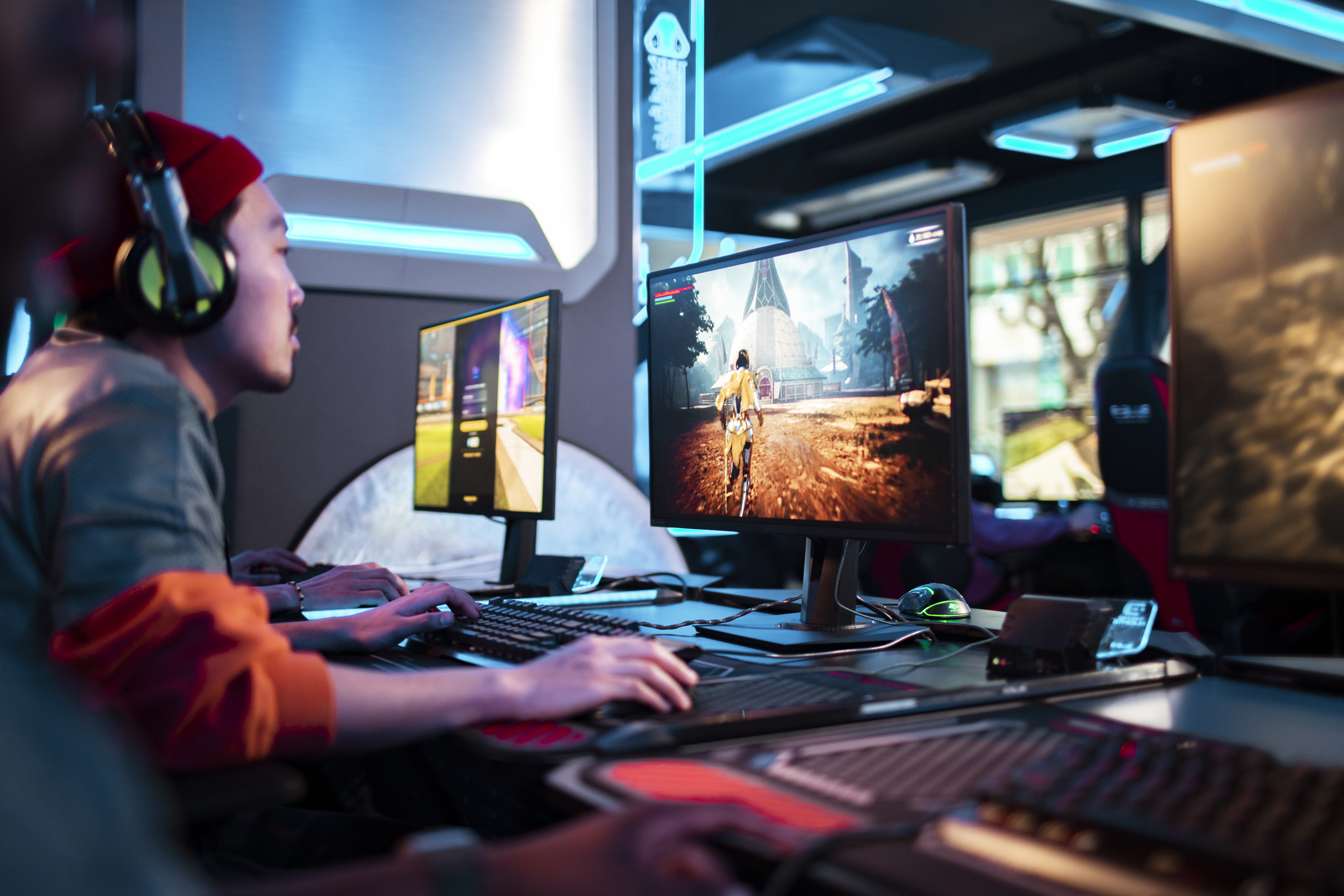 A man playing a computer game at a desk with three screens