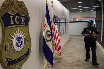 A law enforcement officer walks past ICE logo