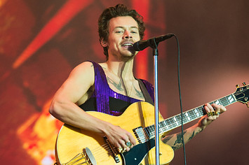 Harry Styles is pictured playing a guitar