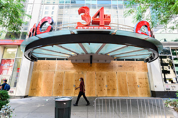 People walk outside the newly boarded AMC 34th Street 14 movie theater in New York City.
