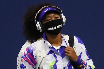 Naomi Osaka walks in wearing a mask with the name of George Floyd on it.