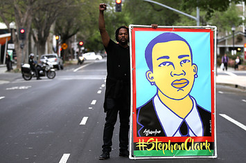 A Black Lives Matter protester holds an illustration of Stephon Clark