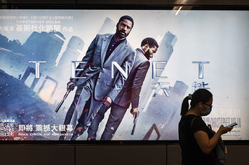 A commuter walks past a poster of Christopher Nolan's blockbuster film Tenet