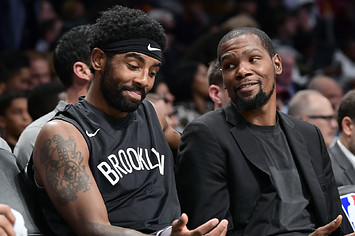Kyrie Irving #11 and Kevin Durant #7 of the Brooklyn Nets speak on the bench.