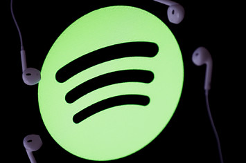 A mobile phone screen displays the logo of Spotify.