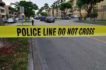 Police tape blocks the street to an apartment building
