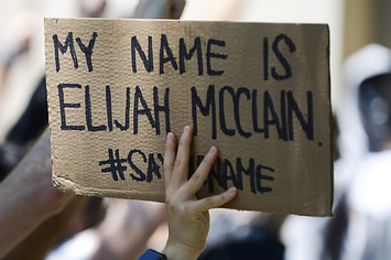 A woman holds sign during rally to demand justice for Elijah McClain.