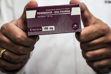 An Egyptian pharmaceutical company employee holds a pack containing vials of Remdesivir.