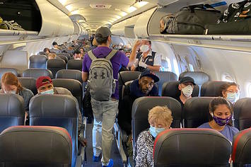 Passengers, almost all wearing facemasks, board an American Airlines flight.
