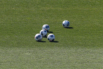 Five balls are lying on the grass of FC Schalke's training facility