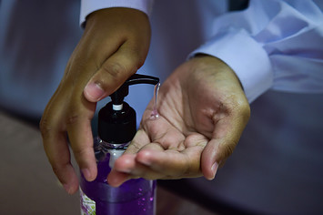 Thai student using hand sanitizer amid coronavirus pandemic.