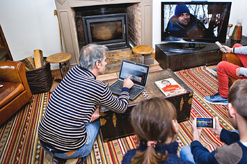 Family in their living room, in front of screens