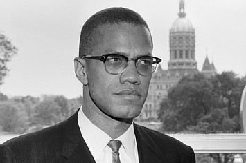 Malcolm X, is shown with the dome of the Connecticut Capitol behind him.