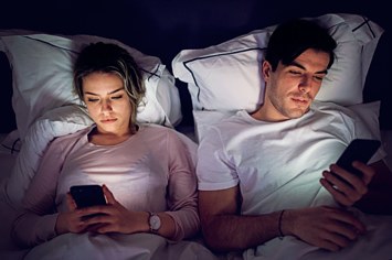 A couple browses the internet in bed.