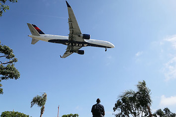 Man watches as a Delta Air Lines plane lands at Los Angeles International Airport.