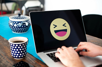A laptop with a happy emoji face displayed