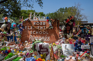 The Robb Elementary School sign is seen covered in flowers and gifts on June 17, 2022