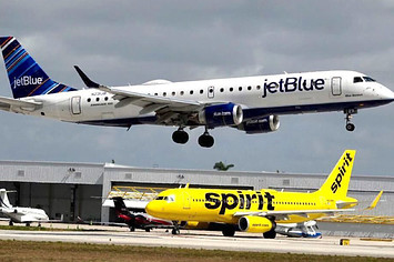 JetBlue airliner flies over Spirit Airlines jet.