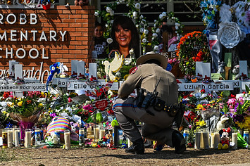 An officer pictured in front of makeshift memorial at Robb Elementary School.