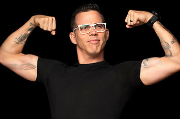 Steve-O poses in front of a black background
