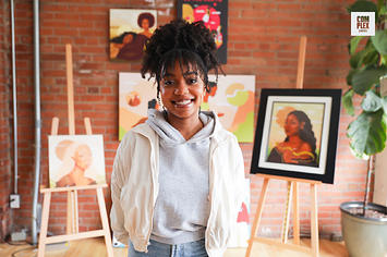 Toronto artist Alexis Exe poses in front of several of her paintings inside her home
