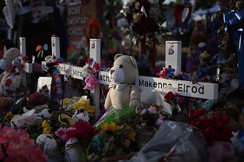 Flowers, plush toys and wooden crosses are placed at a memorial