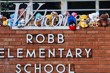 A girl lays flowers at a makeshift memorial at Robb Elementary School