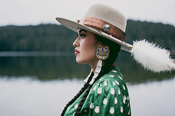 Tia Wood wearing a hat and beadwork earrings, looking to the left