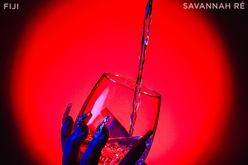 The album art for Savannah Re's single, "Fiji". A liquid being poured into a wine glass being held by a hand with long nails.