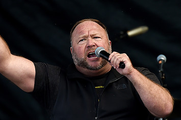 Alex Jones is pictured screaming and holding up a fist