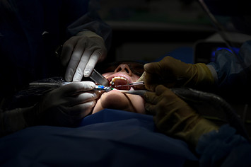Dentists perform a dental procedure.