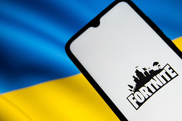 'Fortnite' logo on a smartphone screen with Ukraine flag in the background.