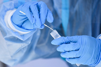 A healthcare worker places a test swab into solution for a PCR Covid test.