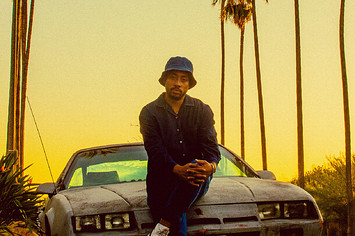 Cadence Weapon sitting on a car