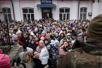 A member of the Ukrainian military gives instructions to women and children that fled fighting