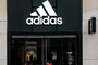 A woman is walking in front of the closed entrance of a department store of the sporting goods manufacturer adidas in downtown Hamburg