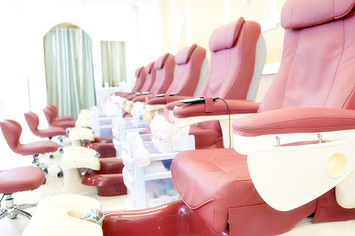 A row of pedicure massage chairs in a row in a clean, bright nail salon small business shop.