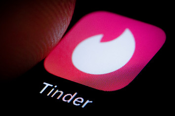 Finger hovers over Tinder app on a smartphone.