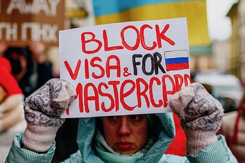 A protester is seen holding a placard that says "Block Visa and Mastercard for Russia"